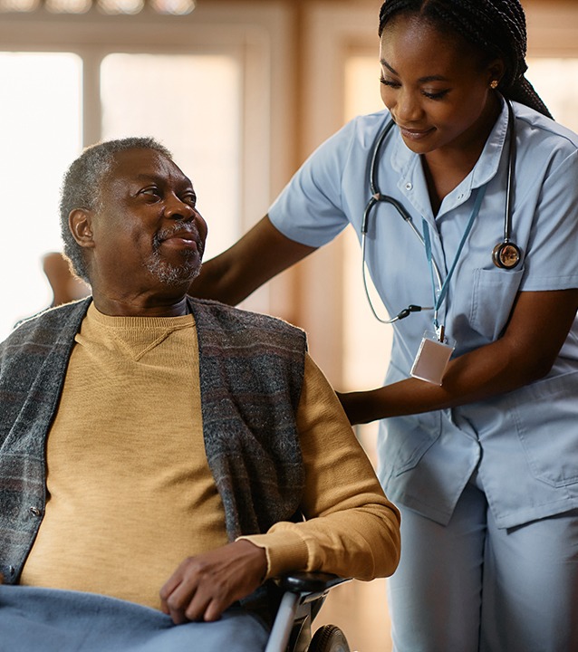 young black nurse assisting a senior man in a wheelchair